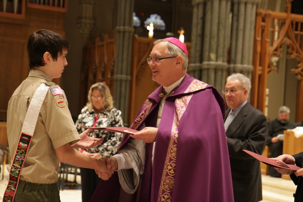 Matthew Jessing receives the Pillar of Faith Award from Bishop Thomas J. Tobin. The award, which represents the depth of a Scout's commitment to exploring their faith, recognizes Scouts who earn all four national Catholic religious scouting awards. Jessing was one of three Boy Scouts receiving the award for Duty to God, having earned the Light of Christ, the Parvuli Dei, the Ad Altare Dei and the Pope Pius XII emblems. The other Scouts were Jeffrey Dowling and Christian Masse. Girl Scout Kaleigh Poirier was also awarded in this category for Service to God, having earned the Family of God, I Live My Faith, the Marian and Spirit Alive Medals.
