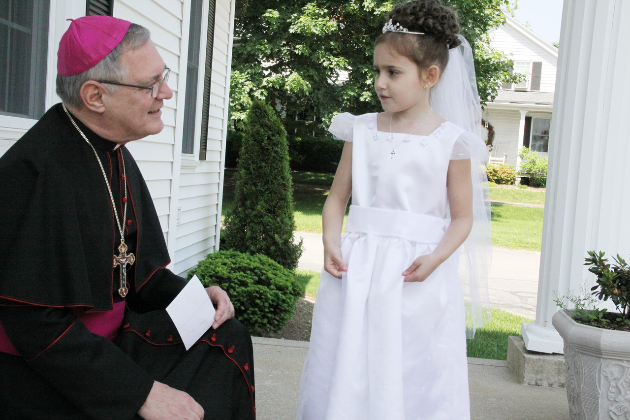Bishop Thomas J. Tobin greets a healthy Sydney Khoury, then age nine and a second-grader, in 2011 outside St. Philip Church, Greenville following a May Crowning Mass.