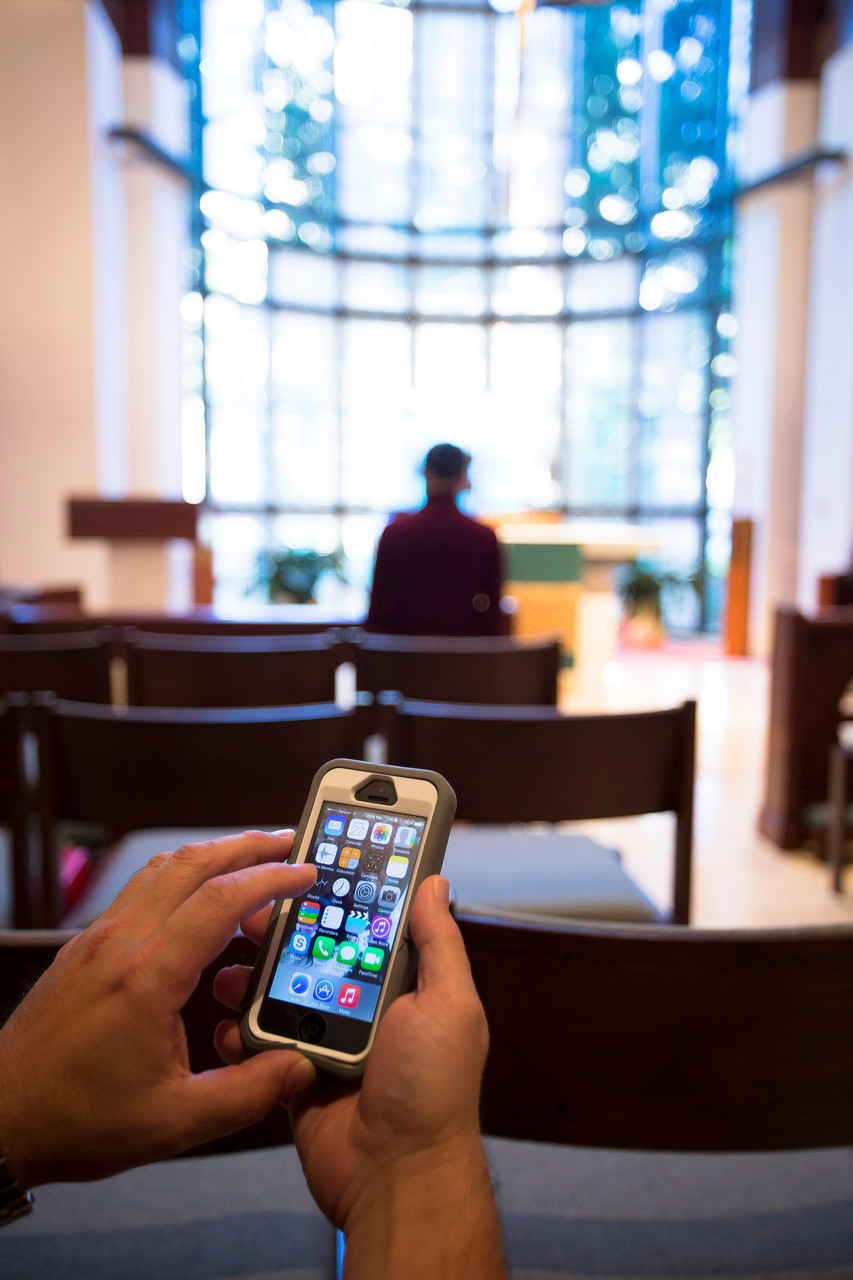 This photo illustration shows someone using a cellphone inside a Catholic chapel in Washington Oct. 27. With cellphones everywhere -- at family meals, in the classroom and at sporting events -- it is no surprise they are at church, too. (CNS photo/Tyler Orsburn) See TEXTING-CHURCH Oct. 27, 2014. Editors: Photo was taken for the purpose of illustration and not during an actual Mass.