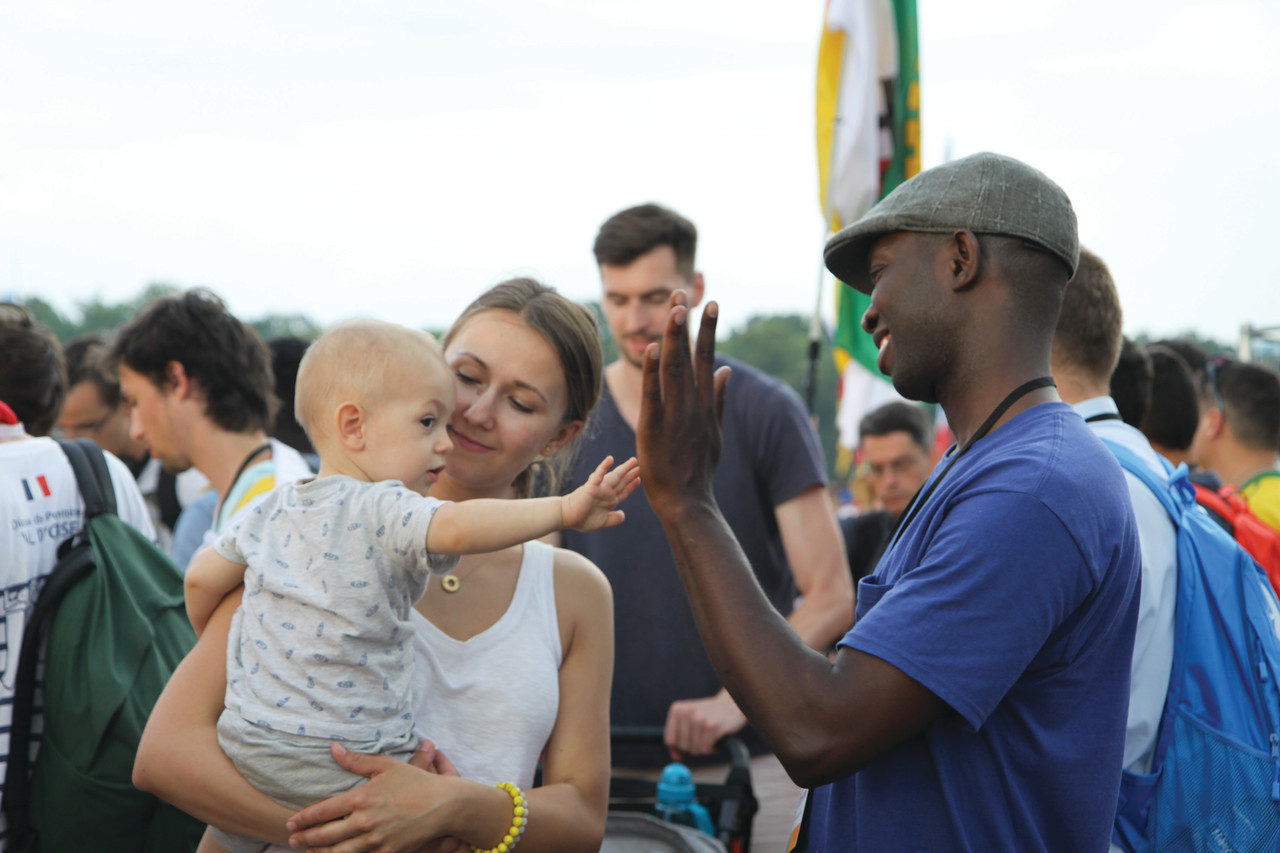 Deacon Joseph Brice offers a high-five to a fellow pilgrim at the opening Mass in Blonia Park on Tuesday.