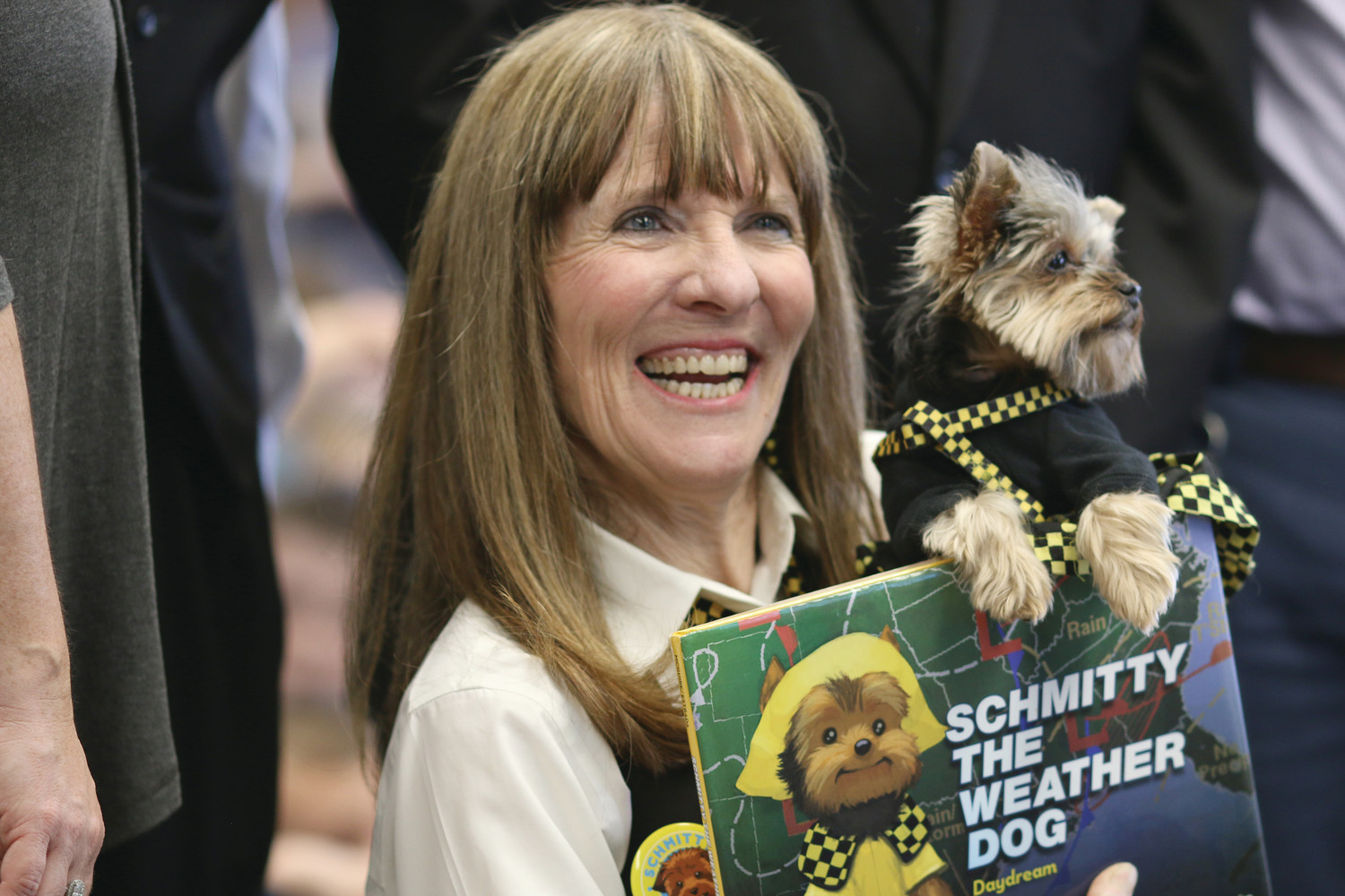 Holding her children’s book named after her beloved pup, Schmitty The Weather Dog, author Elly McGuire, smiles after reading to the students of St. Kevin School in Warwick on Thursday, March 1.
