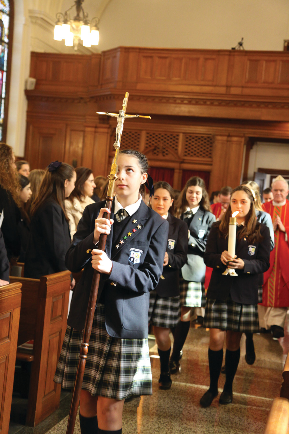 Jimena Ossio carries the cross during a school Mass celebrating the sacrament of confirmation at Overbrook Academy, Greenville. On February 28, twenty-six students received the sacrament at the international Catholic boarding school.