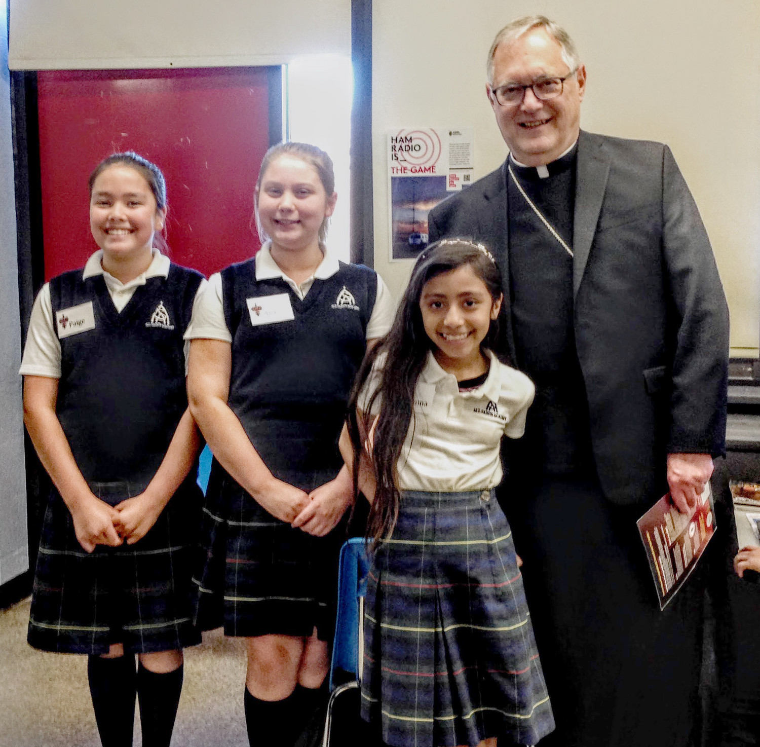 All Saints students Paige, Ava and Arianna with Bishop Tobin following his successful radio contact with a North Kingstown station.