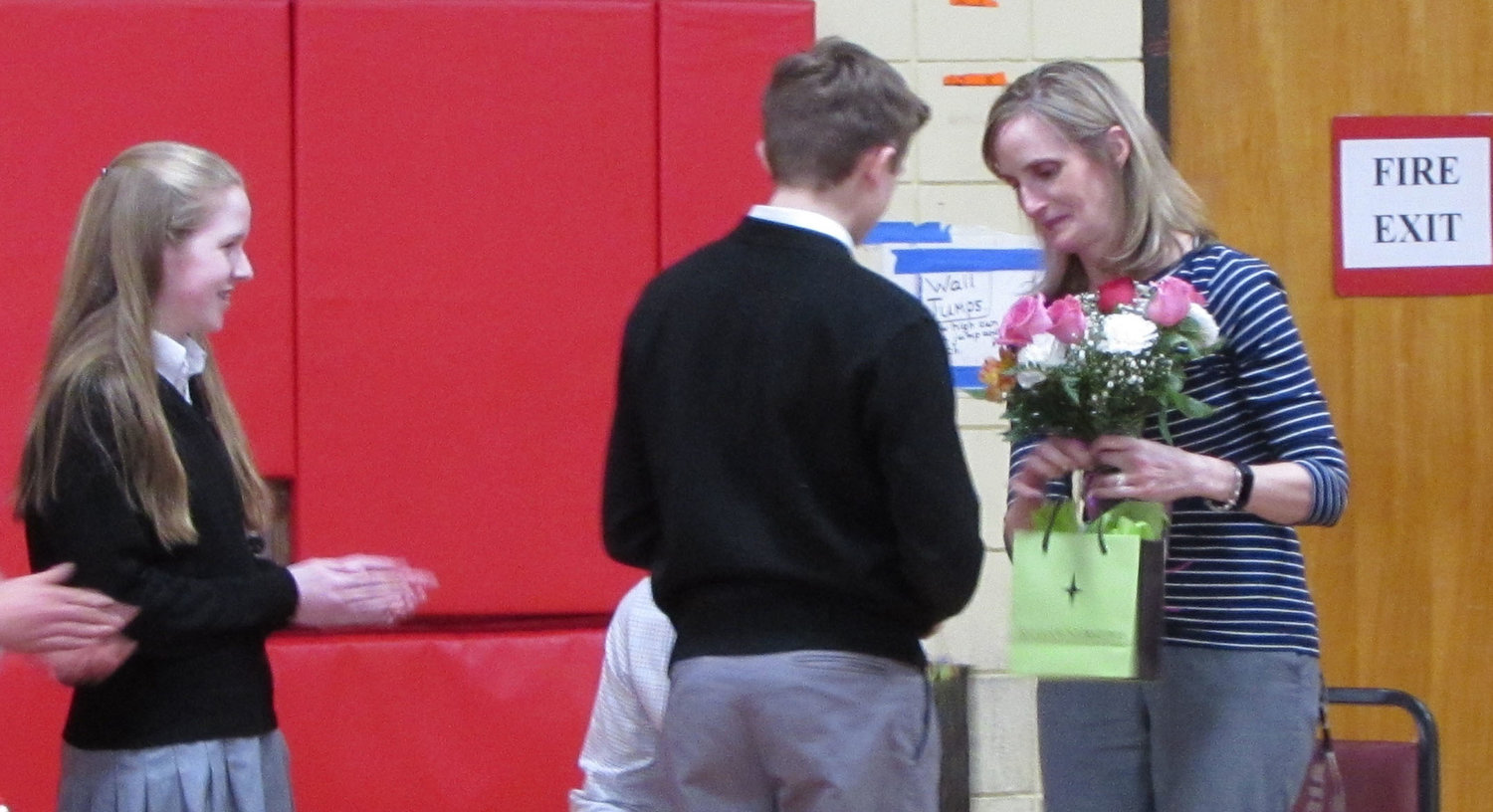 Eighth graders Anna Vredenburg and Ryan Stone present Principal Senenko with gifts and flowers from the school.
