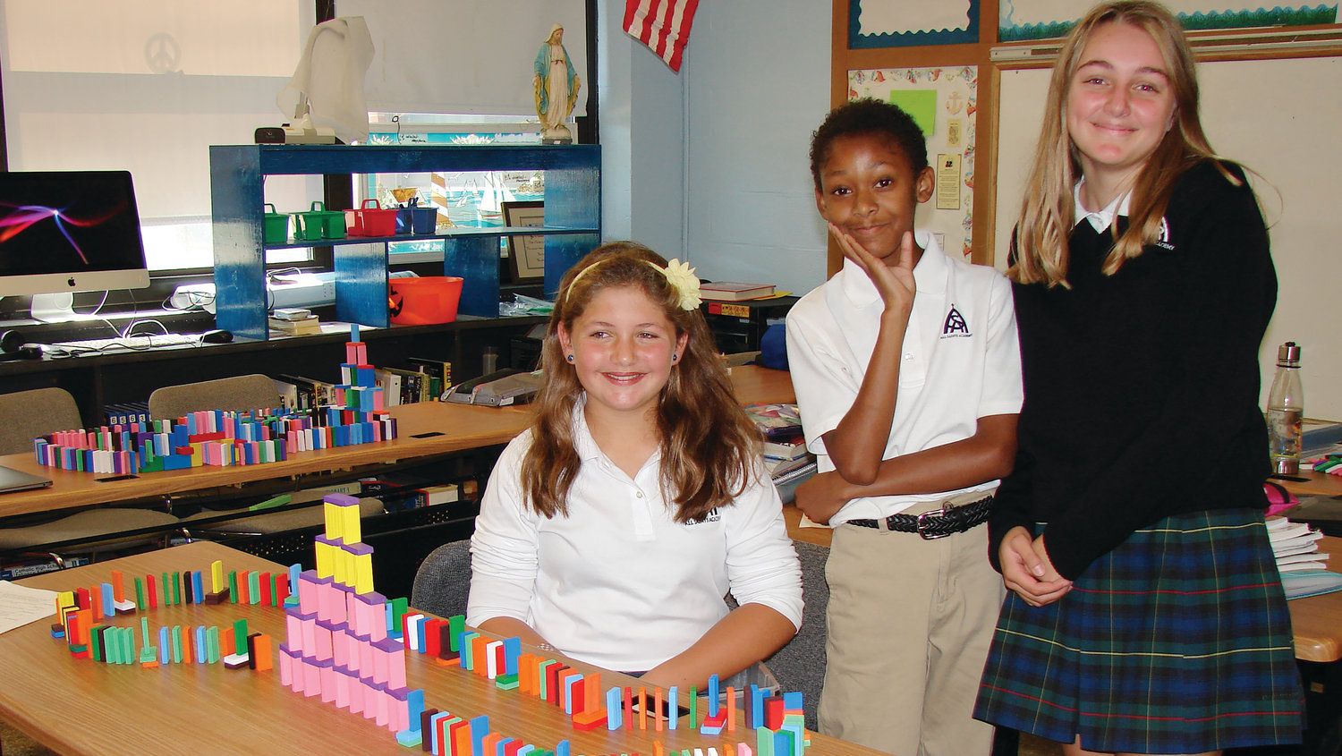 Elizabeth Guild, grade 6, Juelz Harris, grade 6, and Danielle Abosso, grade 8, stand proudly by their moving energy project.