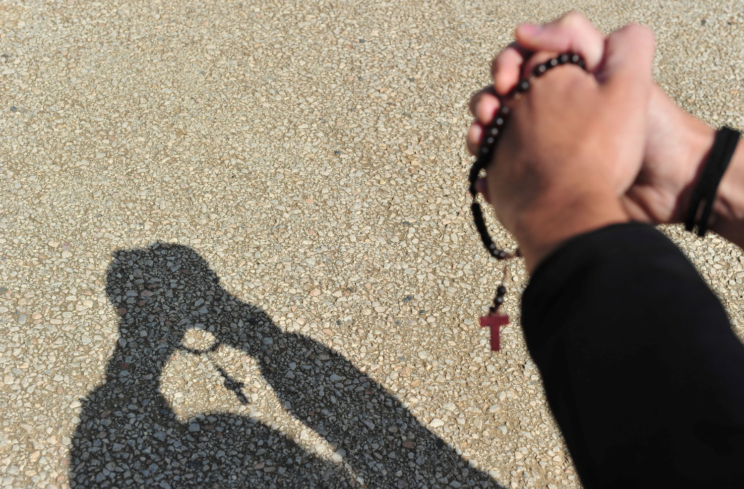 A shadow is cast as a young person prays with a rosary in Grosseto, Italy, March 25, 2020. Joined by Orthodox, Anglican and Protestant church leaders and faithful from around the world that day, Pope Francis led the recitation of the Lord's Prayer, imploring God's mercy on humanity amid the coronavirus pandemic. (CNS photo/Jennifer Lorenzini, Reuters) See POPE-GLOBAL-PRAYER March 25, 2020.