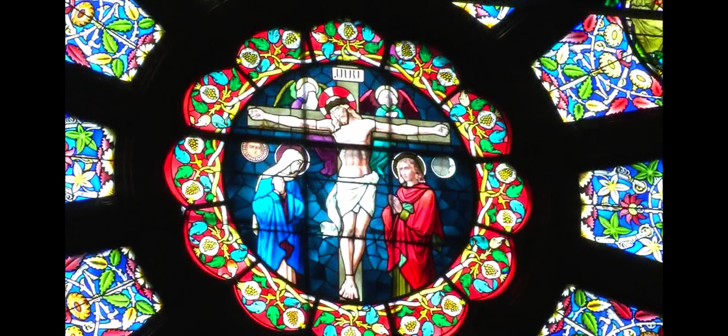 Easter morning sunlight illuminates a stained glass depiction of Christ being crucified on the cross in one of the cathedral’s large rose windows.
