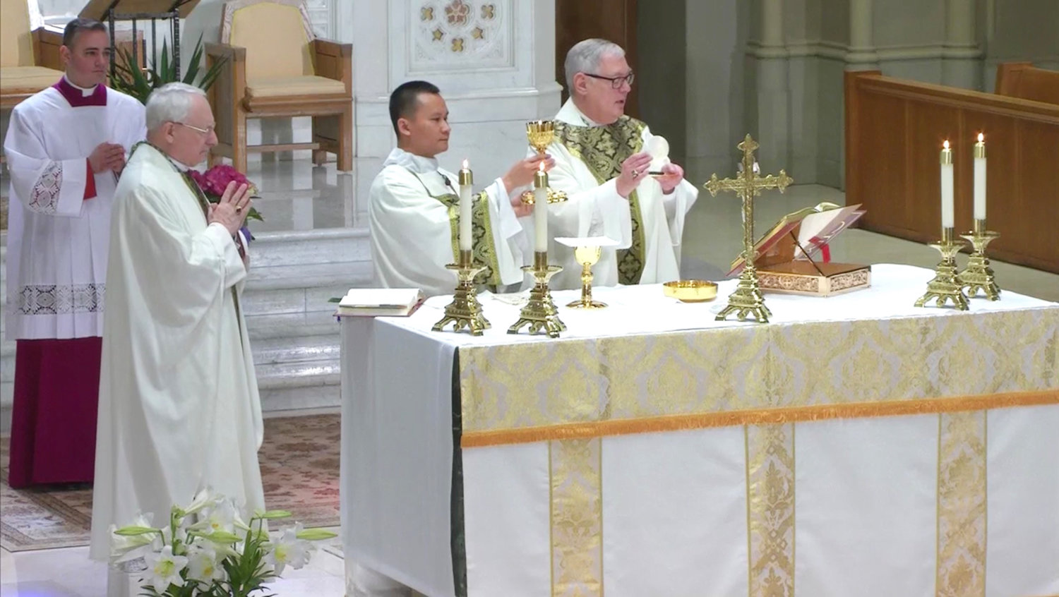 Auxiliary Bishop Robert C. Evans, left, and Bishop Thomas J. Tobin, right, concelebrate, while Deacon Hiep Nguyen, center, assists at the Mass.