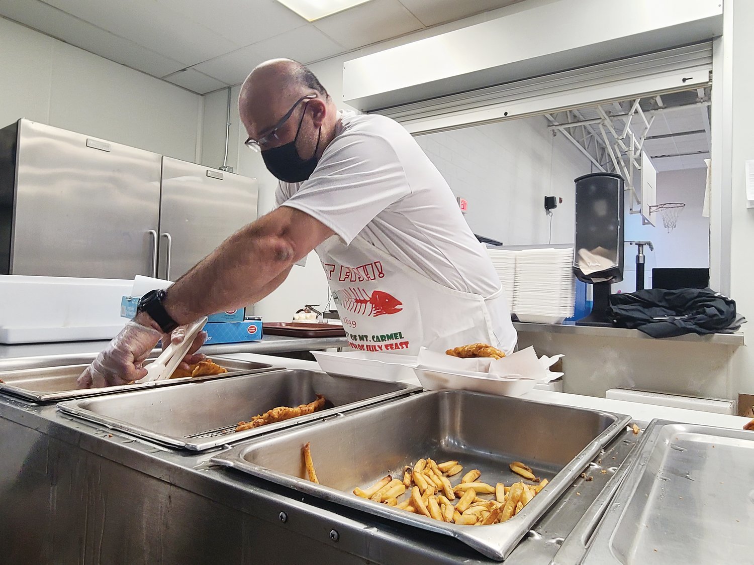Joe Simeone prepares a customer’s fish and chip order during Our Lady of Mount Carmel Church’s drive-through parish fish fry on Friday, March 12.
