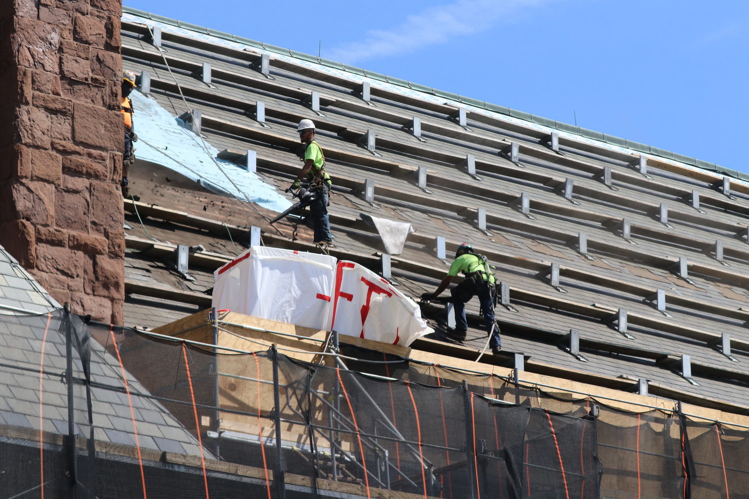 Contractors in the early weeks of the project prepare the roof for new tiles.