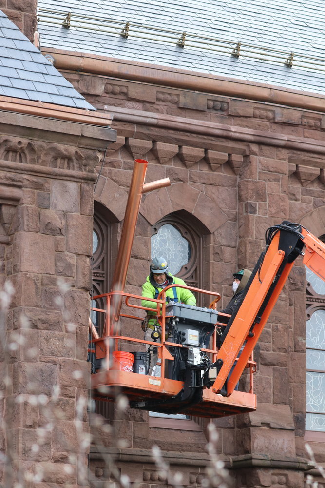 Workers install new copper drain pipes on Feb. 23, in an image that also shows the new copper gutters and one of the two new snow rails on the roof of the Cathedral of SS. Peter and Paul.