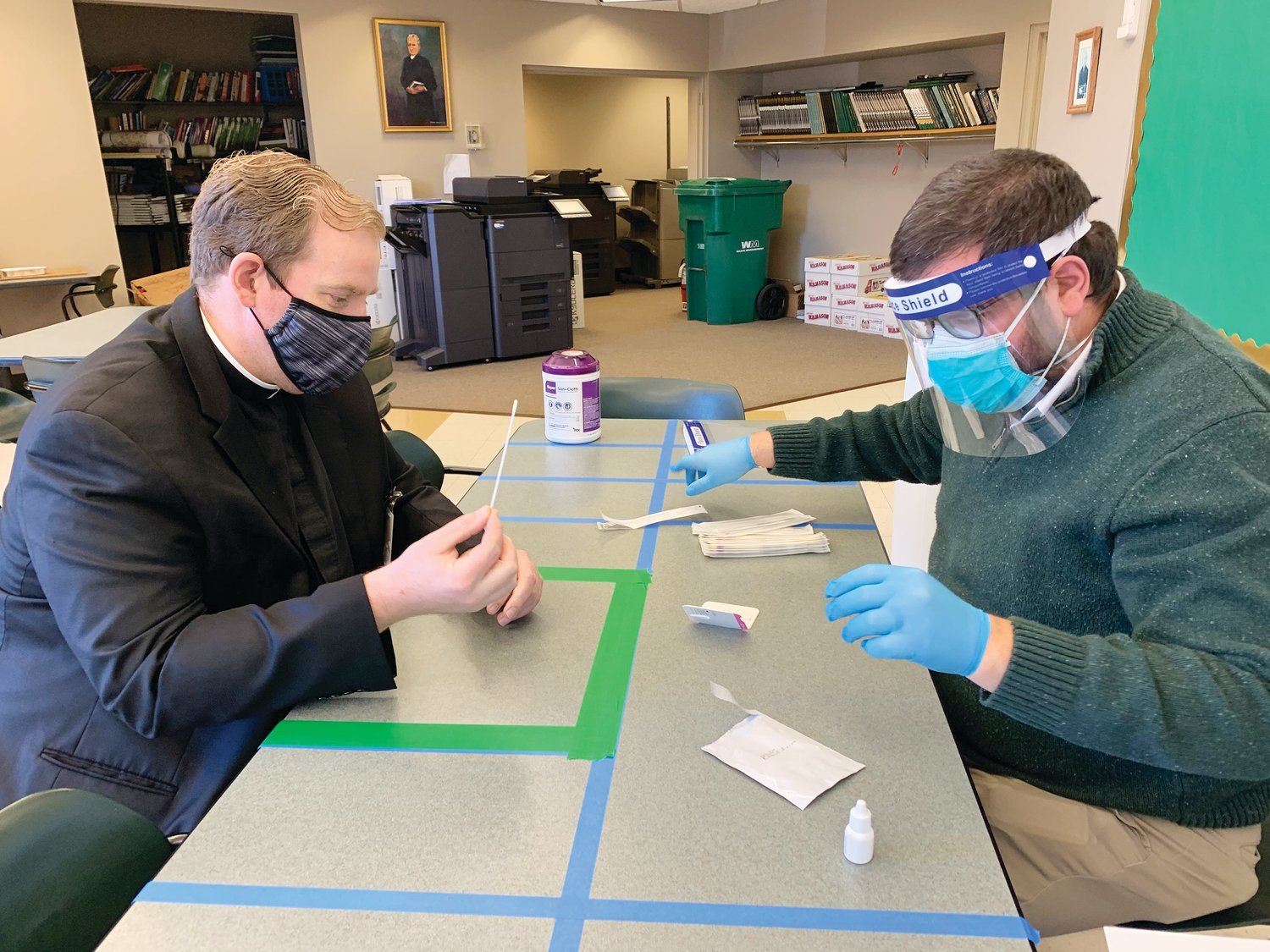 Bishop Hendricken Chaplain Father Brian Morris is about to undergo the first nasal self-administered swab of the new BinaxNOW Asymptomatic Surveillance testing program being offered at the school through the RI Departments of Health and Education.