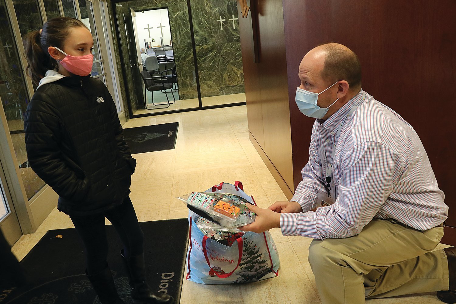 Mia RIcci, 9, presents gift bags that she prepared for guests staying at the diocesan Emmanuel House homeless shelter to James Jahnz, diocesan supervisor of Catholic Social Services, at the chancery.