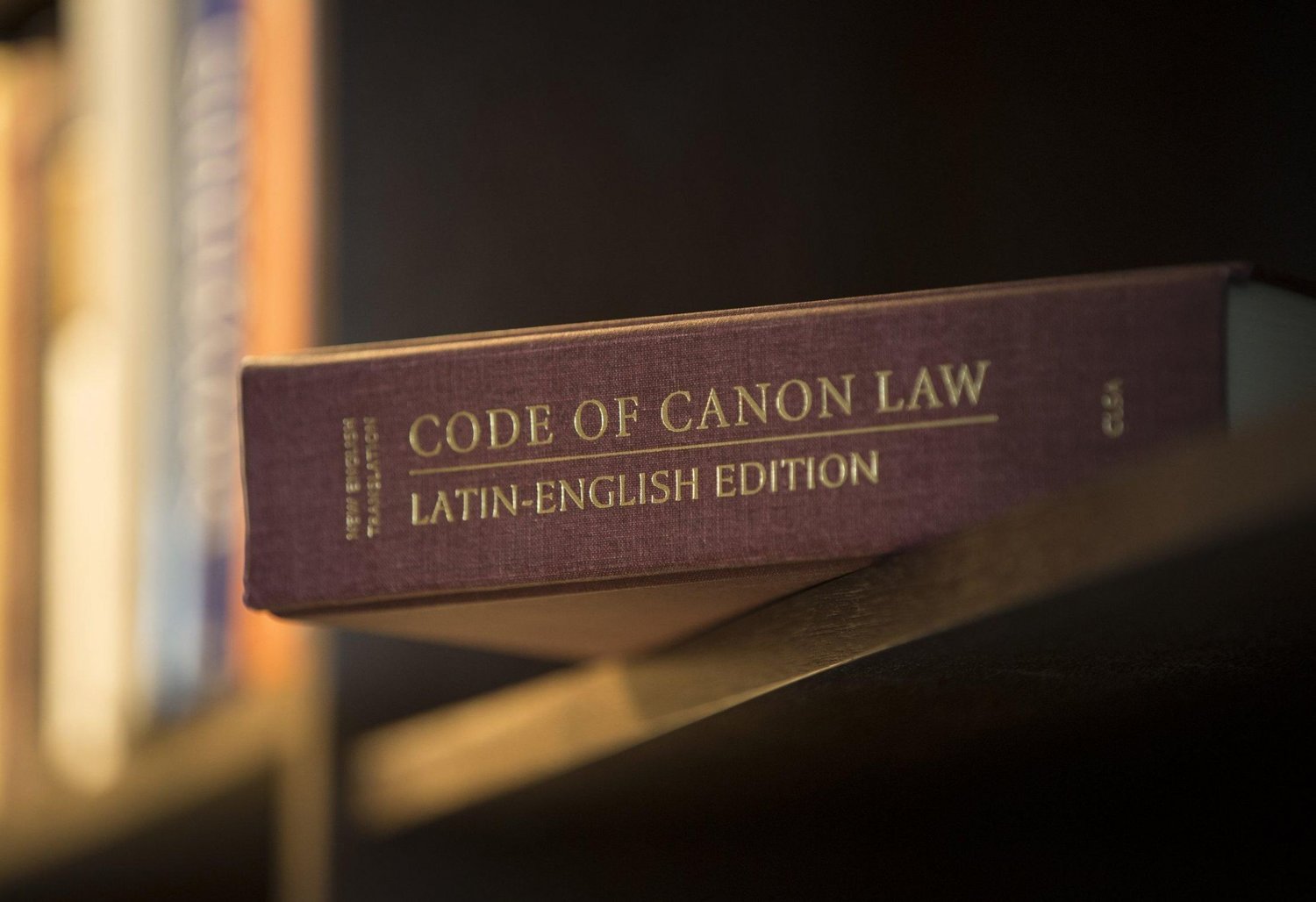 A Latin-English edition of the Code of Canon Law is pictured on a bookshelf. New canon law provisions approved by Pope Francis are expected to help the Catholic Church safeguard against abuse.