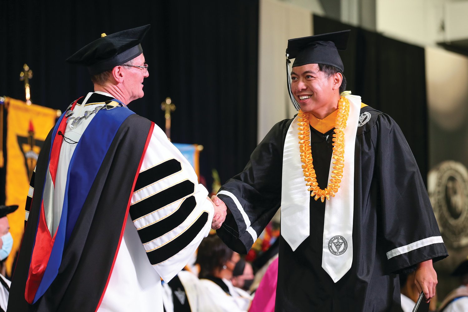 Newly installed PC President Father Kenneth Sicard, O.P., congratulates a graduate during PC’s delayed 2020 Commencement Exercises at the Peterson Recreation Center Sunday.