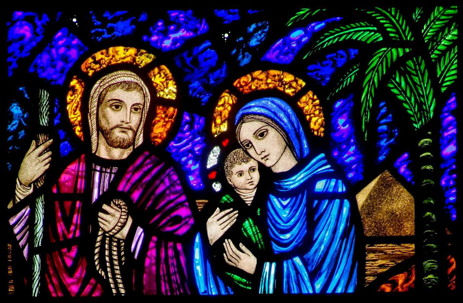 A detail of a stained-glass window from St. Edward's Church in Seattle shows Jesus, Mary and Joseph on their flight into Egypt. (CNS illustration/Crosiers)