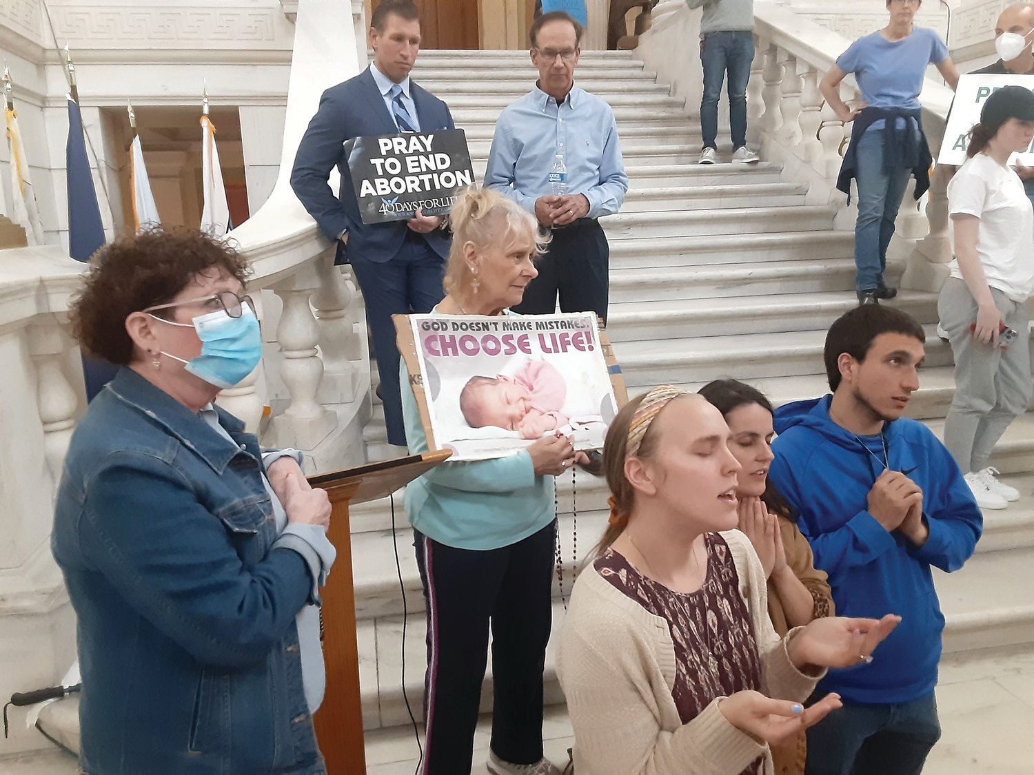Pro-life supporters offer their prayers for the unborn on the main staircase inside the Statehouse while waiting for the House Finance Committee to begin hearing a bill that would use taxpayer funding to pay for abortions.