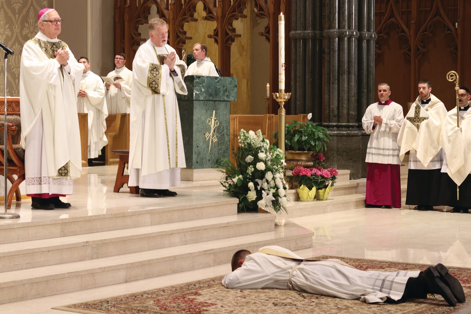 Father Mark Gadoury lays prostrate as the bishop and all gathered pray the Litany of the Saints earlier in the Mass.