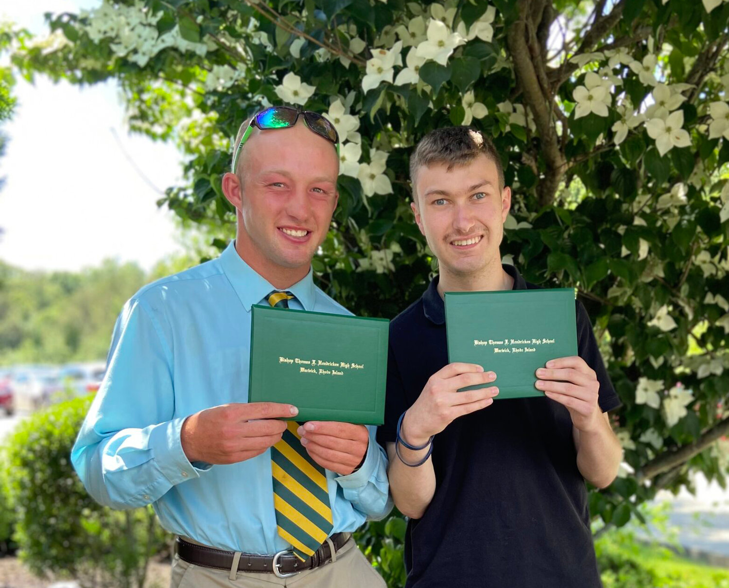 From left, Stephen Baker and Mike Castelli smile as they hold their diplomas from Bishop Hendricken High School