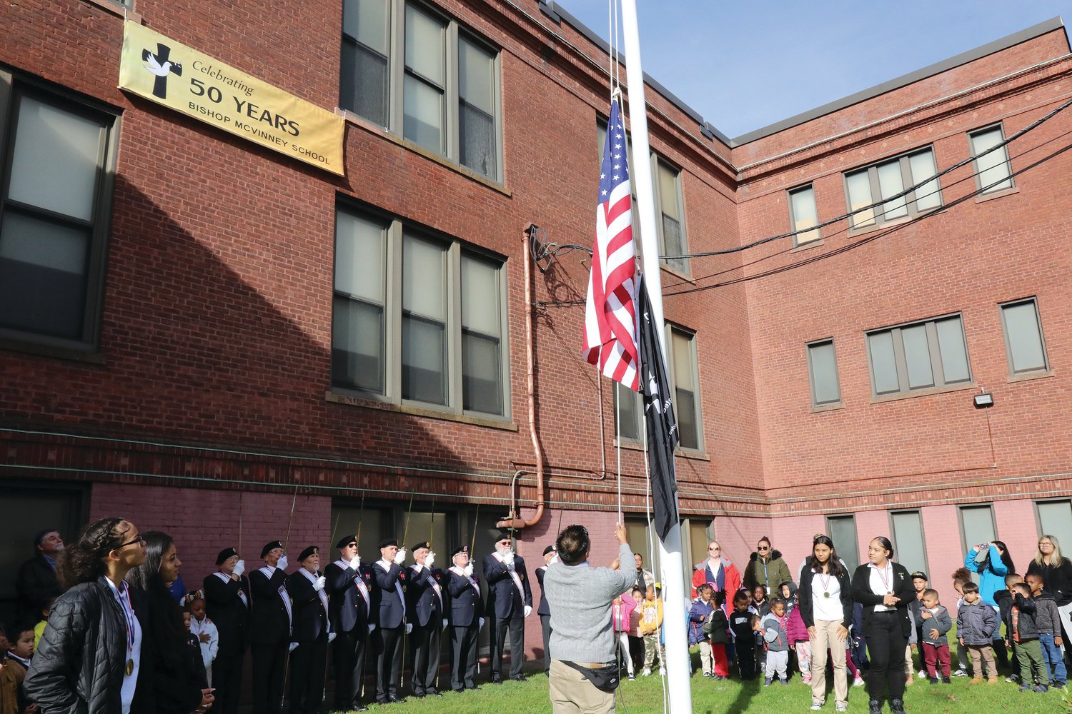 In the 97 years since the red brick school building that’s housed both St. Michael School, and now Bishop McVinney School for the past 50 years, there was never a flagpole on grounds. The Knights of Columbus stepped in to change that history, raising the $2,500 needed to install a flagpole on the lawn.