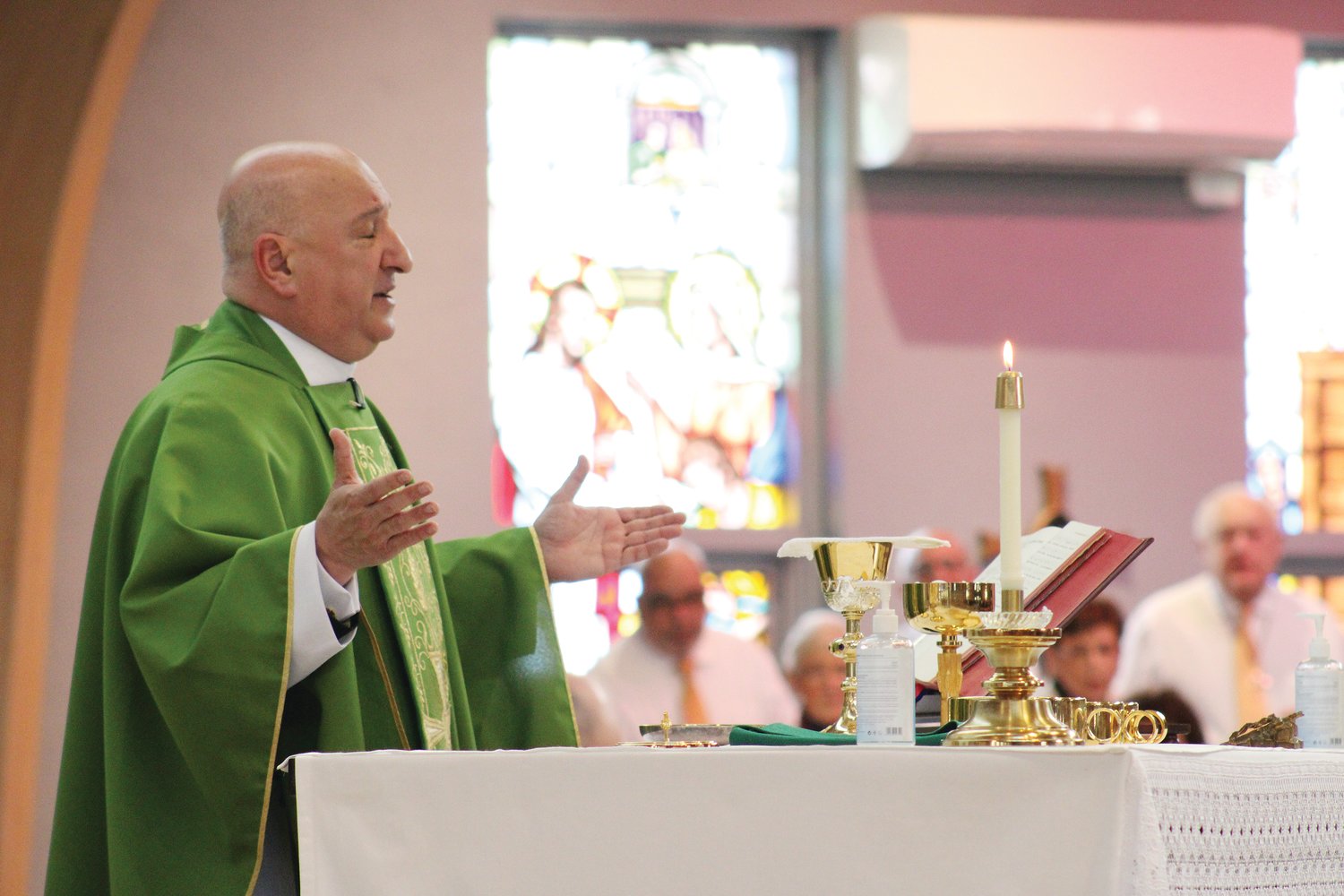 Father Marciano celebrates Holy Mass at St. Kevin Church, as the choir sings, during a memorial Mass for all those who perished in the Station Nightclub Fire, twenty years ago in West Warwick. The pastor expressed his gratitude to the emotional and spiritual support given by the first responders and those who helped the survivors and the families of the victims.