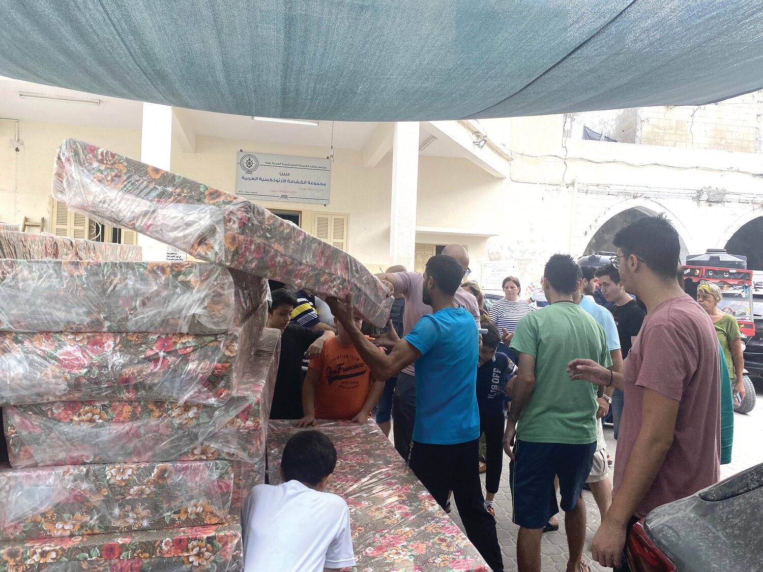 Gazans in need of shelter pick up mattresses purchased by CNEWA to help those displaced.