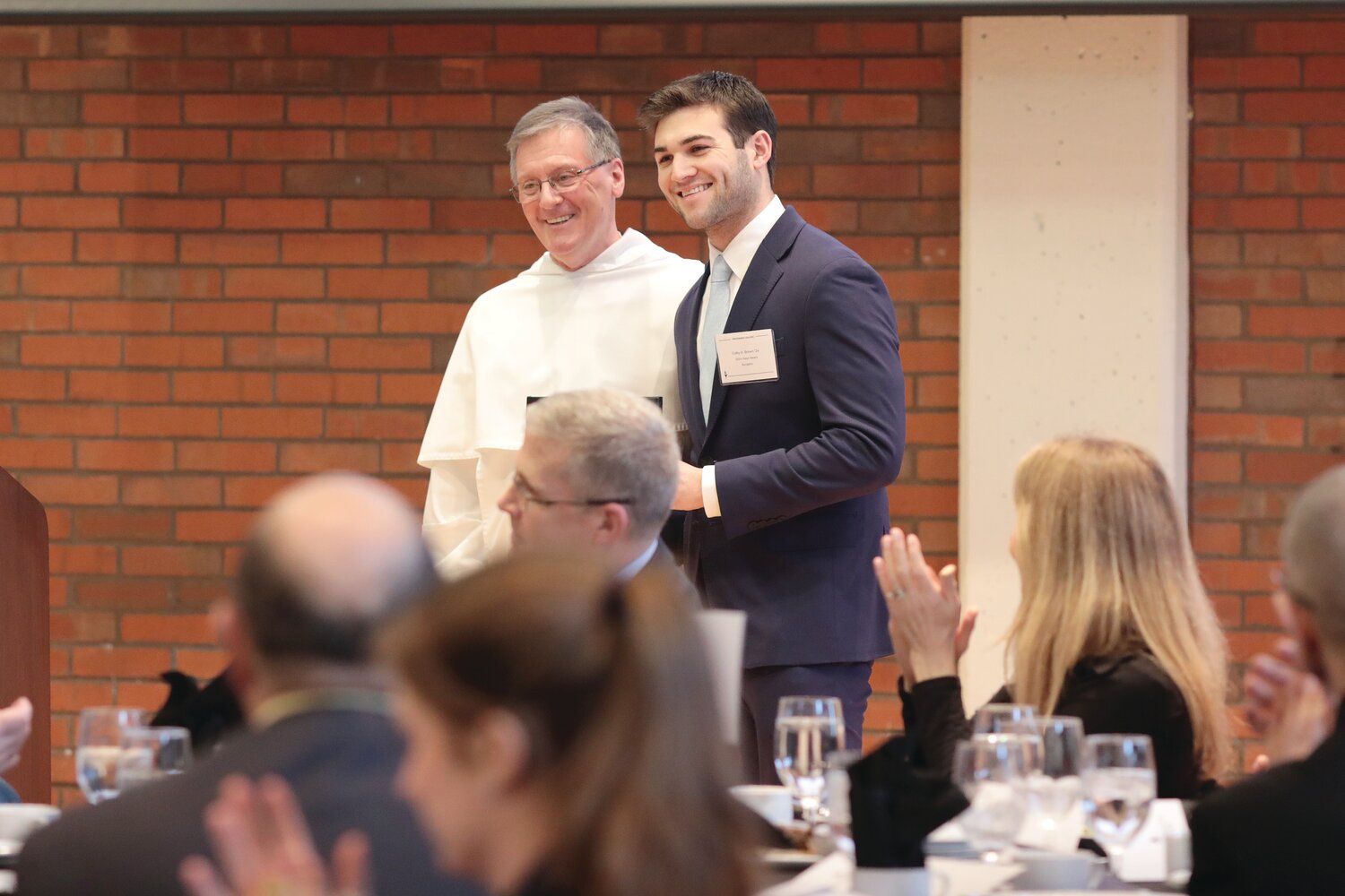 Providence College President Father Kenneth R. Sicard, O.P., presents Colby Brown, co-founder of the Rhode Island chapter of First Generation Investors, and Kerri Murray, President of ShelterBox USA, with their Dr. Martin Luther King, Jr. Vision Awards.