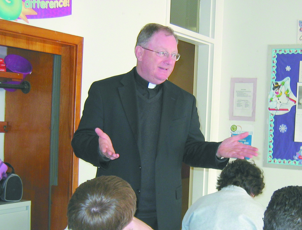 MAKING A POINT:  Father Unsworth offers an explanation during a religion class at St. Brendan School.